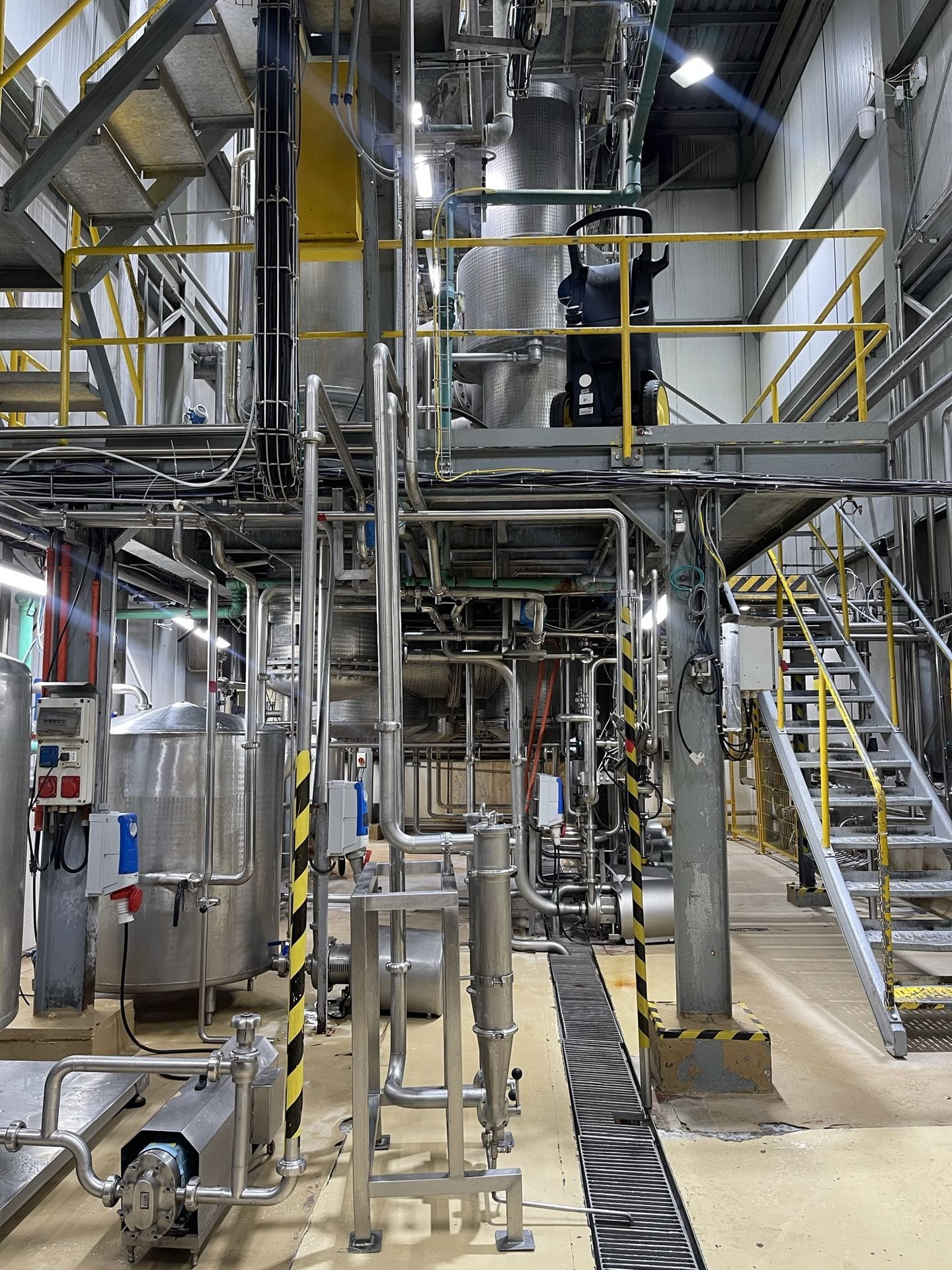 Interior de planta industrial con tanques, tuberías y pasarelas de acceso