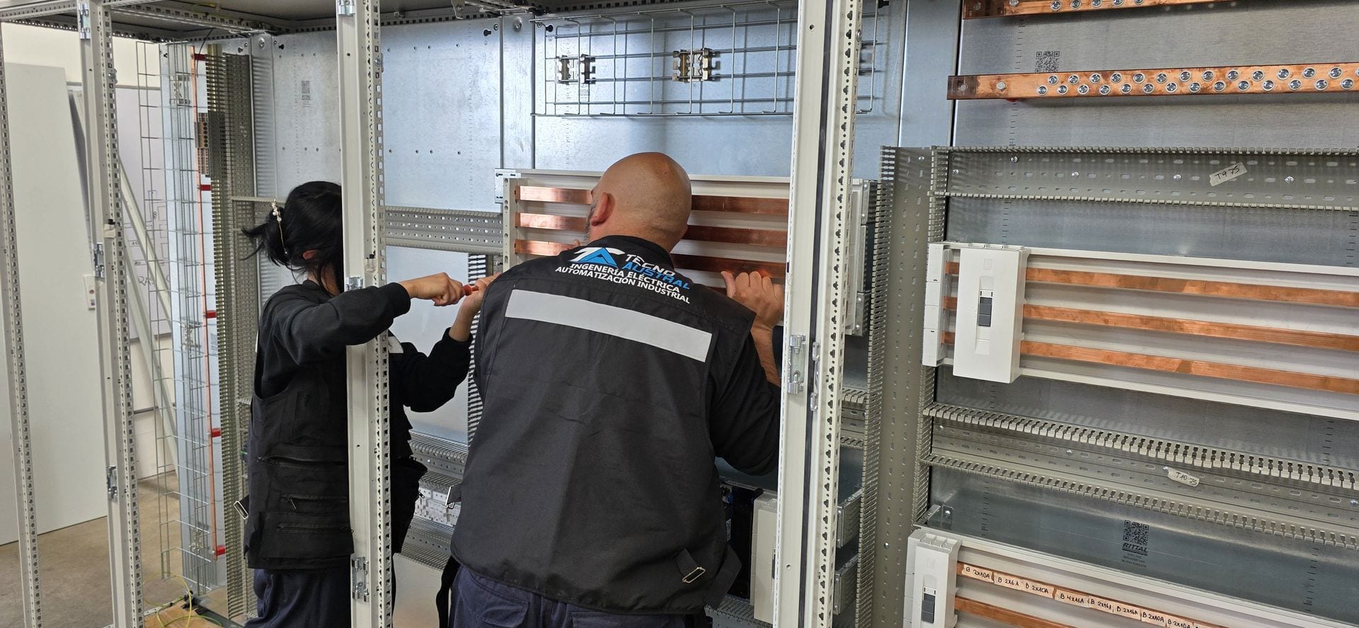 Dos técnicos cableando un gabinete de control en el taller